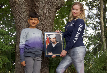 Luke Sukhram (left), 8, and his mother Sabrina Davis (right) stand with a photo of her father, Keith Davis.